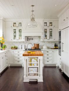 a kitchen with white cabinets and wood flooring is pictured in this image, there are yellow flowers on the counter