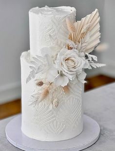 a white wedding cake decorated with flowers and feathers