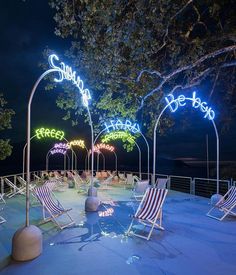 several lawn chairs are lit up with neon lights and the words beach written on them