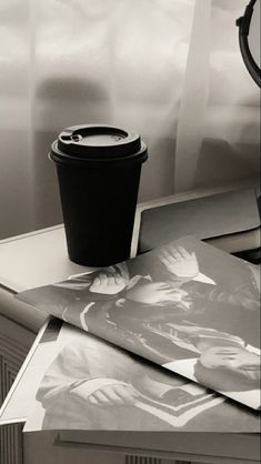 a coffee cup sitting on top of a table next to pictures