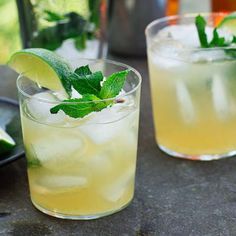 two glasses filled with lemonade, lime and mint garnish on a table