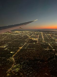 an airplane wing flying over a city at night