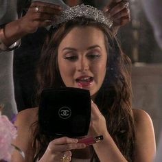 a woman wearing a tiara looking at her cell phone