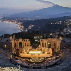 an aerial view of the amphit at night, with lights on and mountains in the background