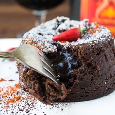 a piece of chocolate cake with powdered sugar on top and a fork in the middle