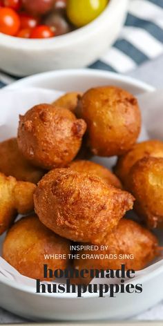 some fried food is in a white bowl on a table with tomatoes and olives