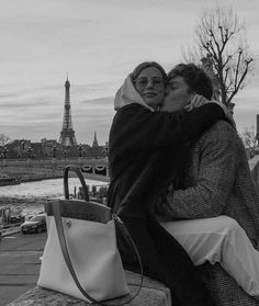 black and white photograph of two people hugging in front of the eiffel tower