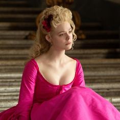 a woman in a pink dress sitting down