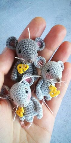 small crocheted mouses with yellow buttons on their ears are being held in the palm of someone's hand