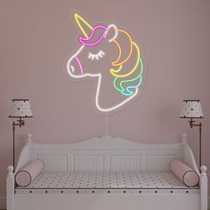 a pink room with a white bed and a neon unicorn head on the wall above it