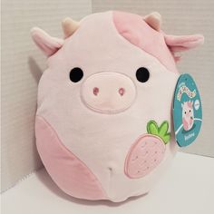 a stuffed animal pig with a strawberry on its nose and black eyes, sitting in front of a white background