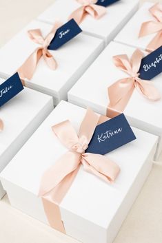 four white boxes with pink bows and name tags on them