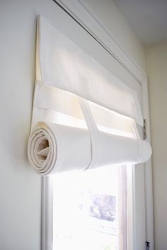 a roll of white fabric hanging on the side of a window