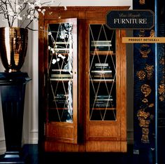 a tall wooden cabinet sitting next to a vase with flowers in it and a sign that says furniture