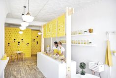 two people standing at the counter in a yellow and white shop