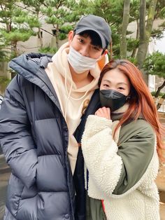 a man and woman wearing masks pose for the camera