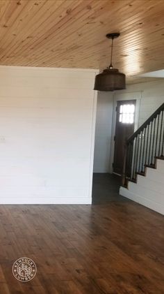 an empty living room with wood floors and white walls, stairs leading to the second floor