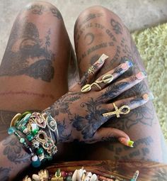 a tattooed woman's legs with rings and bracelets on them