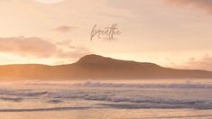 the sun is setting over an ocean with waves coming in to shore and a mountain in the distance