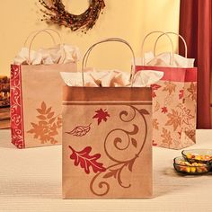 three small bags with designs on them sitting on a table in front of a wreath