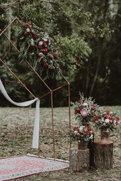 an outdoor ceremony setup with flowers and greenery on the ground next to two vases