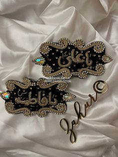 two black and gold brooches sitting on top of a white satin covered bed