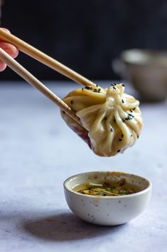 someone holding chopsticks over a bowl of soup