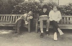 three young men sitting on a wooden bench