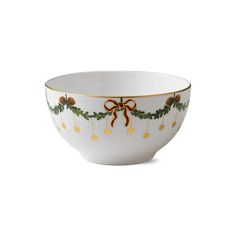 a white bowl with gold trimmings and bows on the side, decorated with holly