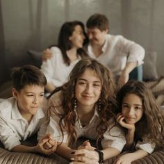 three children are laying on the bed with their parents