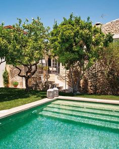 an empty swimming pool in the middle of a yard with trees and bushes around it