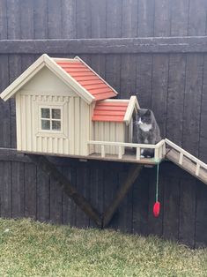 a cat sitting on top of a wooden house