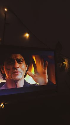 a television screen with a man on it's face and lights in the background