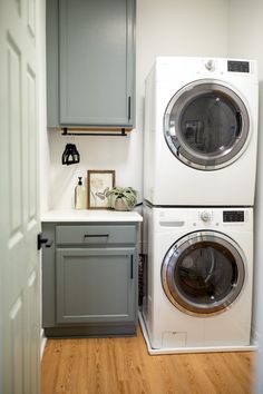 a washer and dryer in a small room with wood flooring on the side