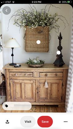 a wooden cabinet with a basket on top and flowers in the middle, next to a lamp