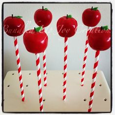 four red and white striped candy canes with apples on them in the shape of lollipops