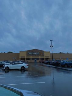 cars are parked in front of a walmart store on a rainy day at dusk