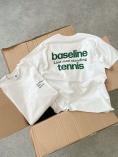 two t - shirts sitting on top of a cardboard box with the words baseline last man standing tennis