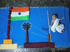 a baby laying on top of a blue blanket next to a flag and some kites