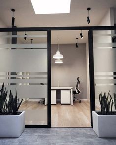 an office with two planters in front of the glass doors that lead into the room