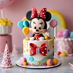 a minnie mouse birthday cake with balloons and confetti