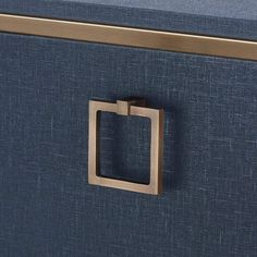 a close up of a metal handle on a blue fabric drawer with gold trimming