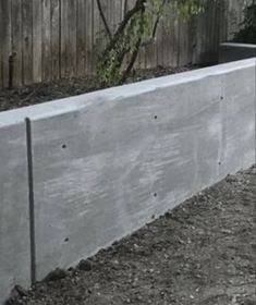 a concrete planter in the ground next to a fence