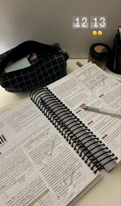 an open notebook sitting on top of a desk next to a pen and calculator