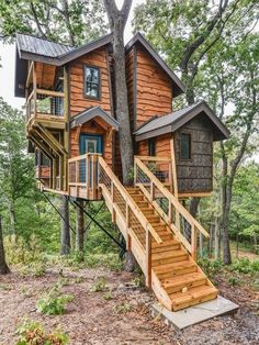 a tree house with stairs leading up to the upper level and second story, surrounded by trees