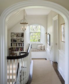 an archway leading to a living room filled with furniture and bookshelves on either side of the stairs