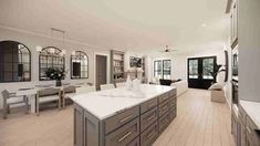 a large kitchen with white counter tops and wooden flooring next to a dining room table