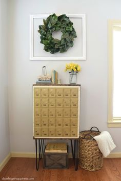 a wooden cabinet sitting next to a wall with a wreath on it and two baskets