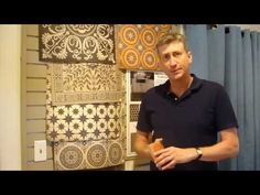 a man is standing in front of some wall hangings and looking at the camera