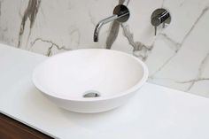 a white bowl sink sitting on top of a counter next to a faucet